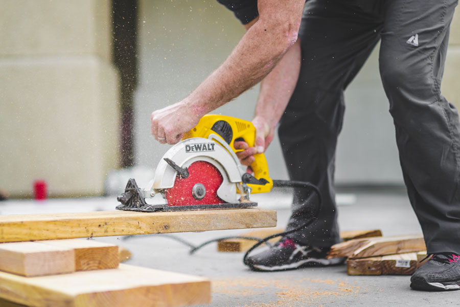 greyson-joralemon-482879-unsplash_man-in-black-sweatpants-using-DEWALT-circular-saw-and-cutting-a-wood-plank900.jpg